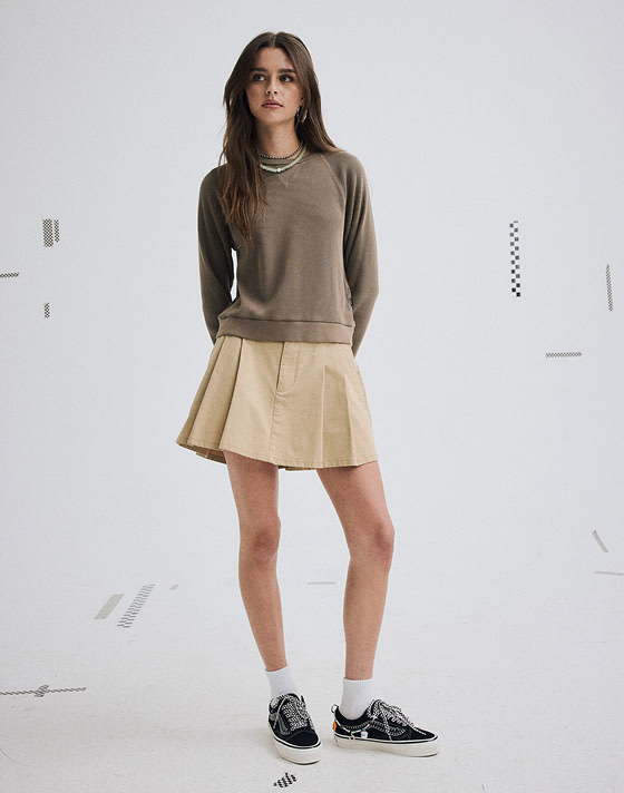 A young woman poses in a photo studio wearing an incense brown Authentic Chino Mini Skirt and Cocona Premium Old Skool.