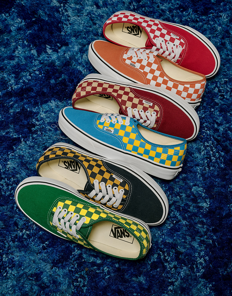 A variety of Checkerboard colorways on the Authentic shoe lie on a plush blue rug.