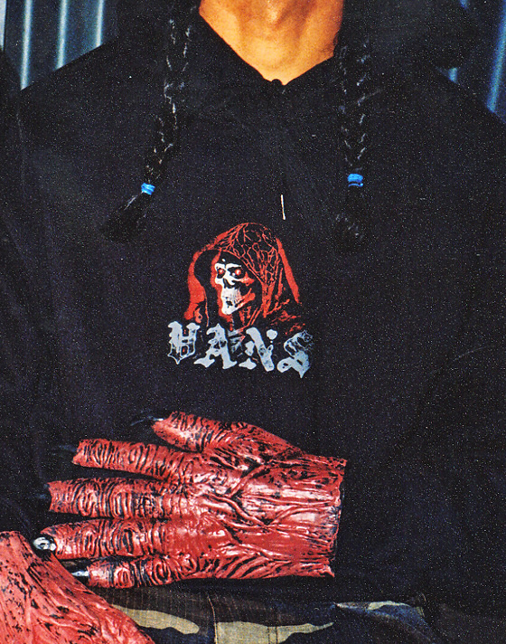 Close up shot of someone's chest with their hands folded across while they’re wearing red ghoul hands and the Sinister Pullover Sweatshirt.