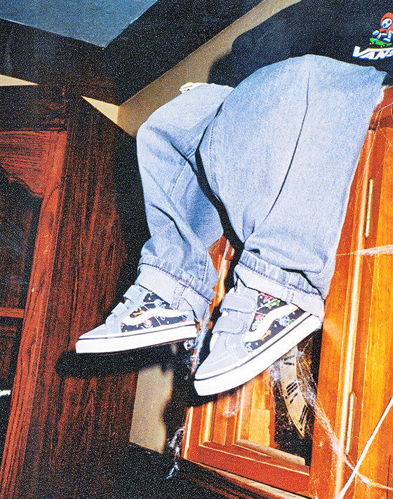 Waist down shot with a little skeleton on a dresser dressed in jeans and the Little Kids Sk8-Mid V Shoe in Glow-in-the-Dark Pewter Grey / Black.