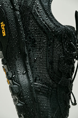 Black Vans shoe with rugged construction, Vibram outsole, and water droplets on the surface.
