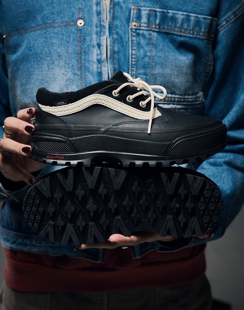 Close-up on someone holding The Standard Low Boot in black and white against a denim jacket.
