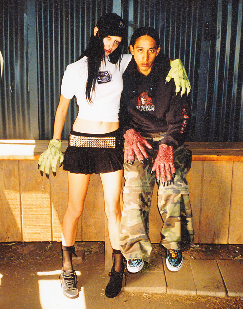 A young man and woman pose wearing shoes and clothes from the Vans Halloween collection and wearing monster gloves.