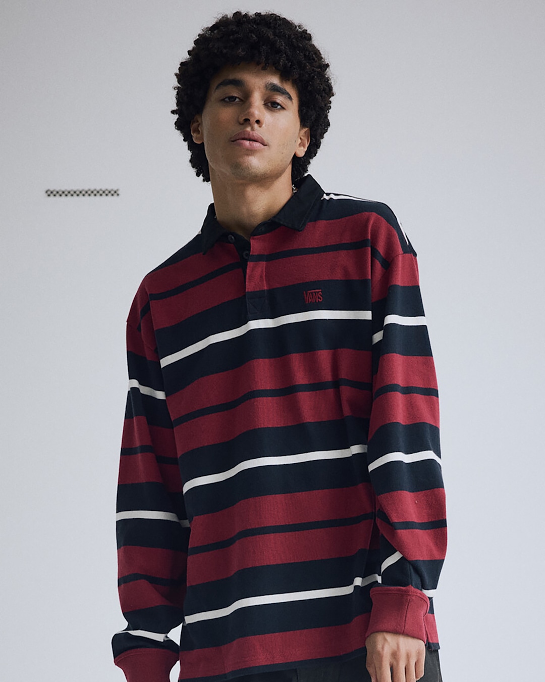 Person wearing a long-sleeve rugby shirt with red, navy, and white horizontal stripes against a light gray background. Text reads 'Stripes.'