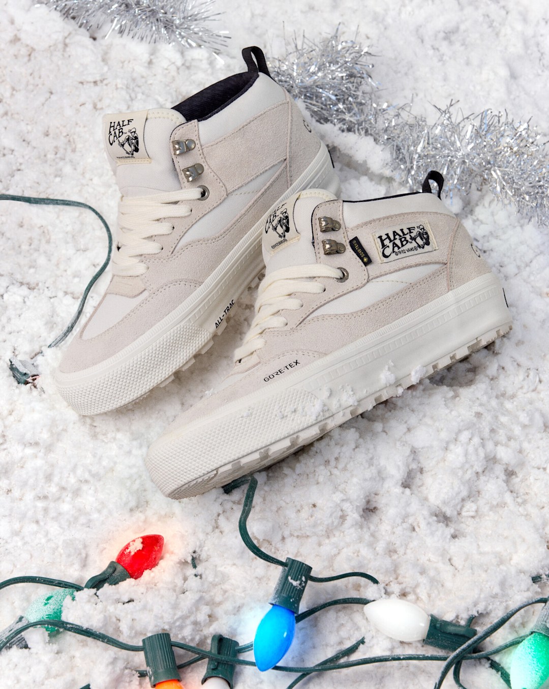 Light-colored Vans Weatherized high-top shoes displayed in snow with holiday lights and the text "Weatherized."