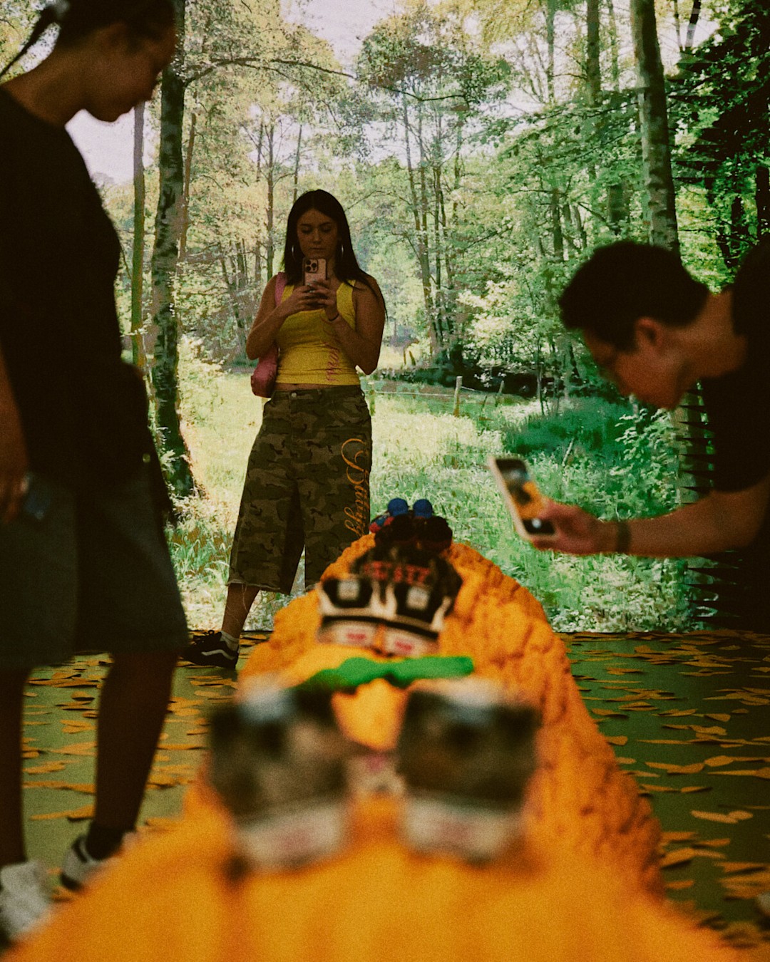 Attendees view and photograph footwear displayed within a forest-themed immersive exhibit.