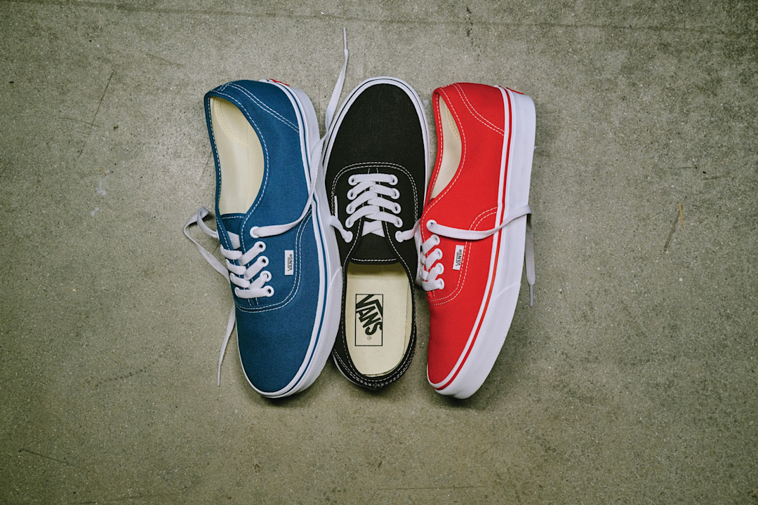 Vans Authentic in blue, black and red unlaced on concrete.
