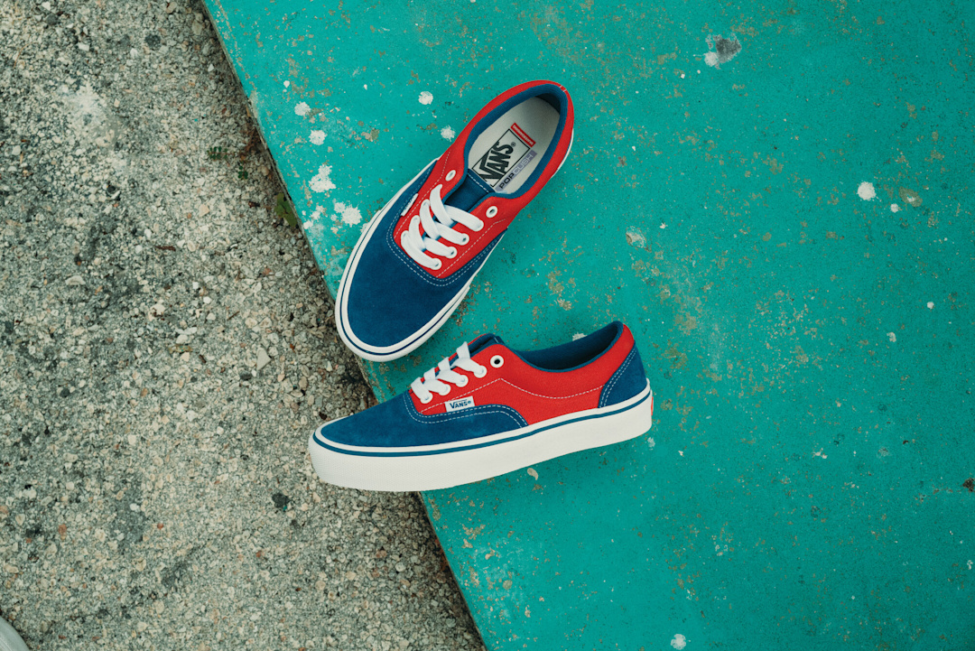Focused shot of Vans Skate Era in red and blue, positioned on concrete with the left shoe showing the sidewall.