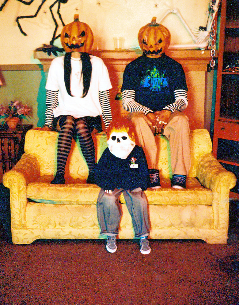 Three people sit on a sofa wearing Halloween masks and clothes from the Vans Halloween collection.