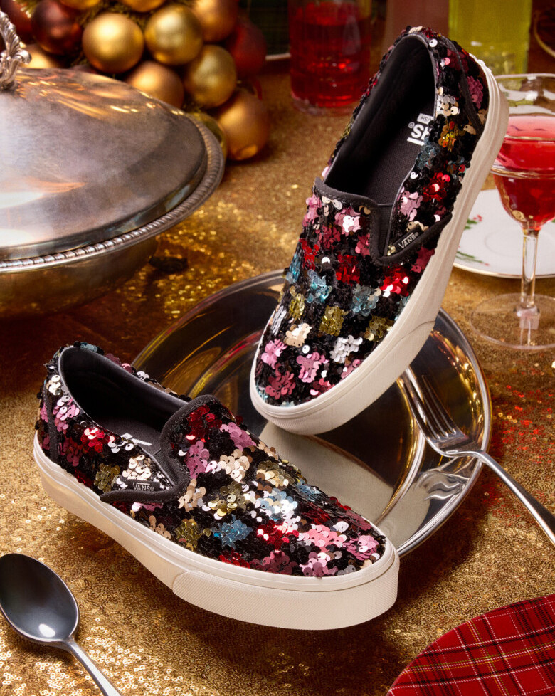 A pair of Vans sequined classic slip on posed on a dish platter with dinner setting behind it for a holiday dinner party.