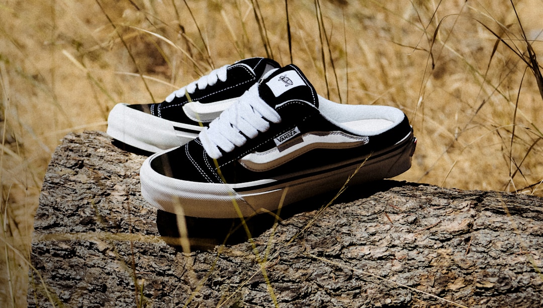 Vansza Knu Skool Mule in black and white resting on a log in a natural outdoor setting.