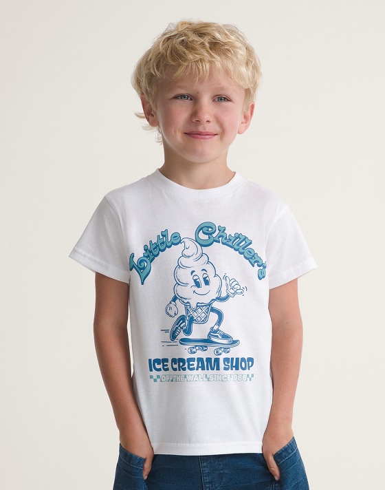 A young boy wearing a white and blue Little Chillers graphic tee in a photo studio.