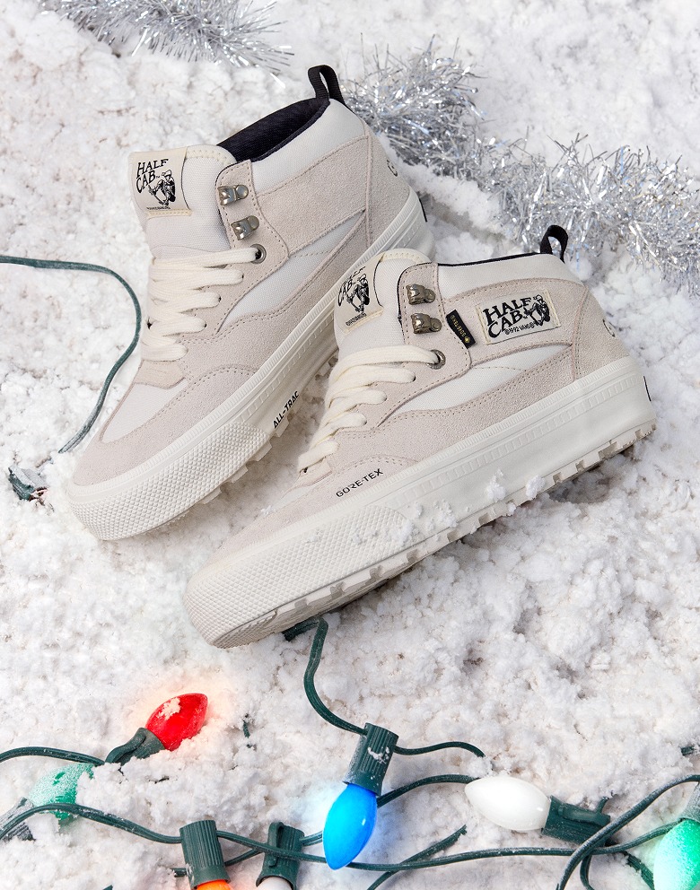A pair of marshmallow white Half Cab GORE-TEX Insulated Shoes on the snow next to Christmas lights.