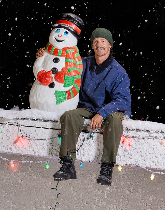 Geoff Rowley, de la saison 2 de « Meet the Vans », est assis sur un toit enneigé, à côté d'un bonhomme de neige en plastique qui s'illumine.