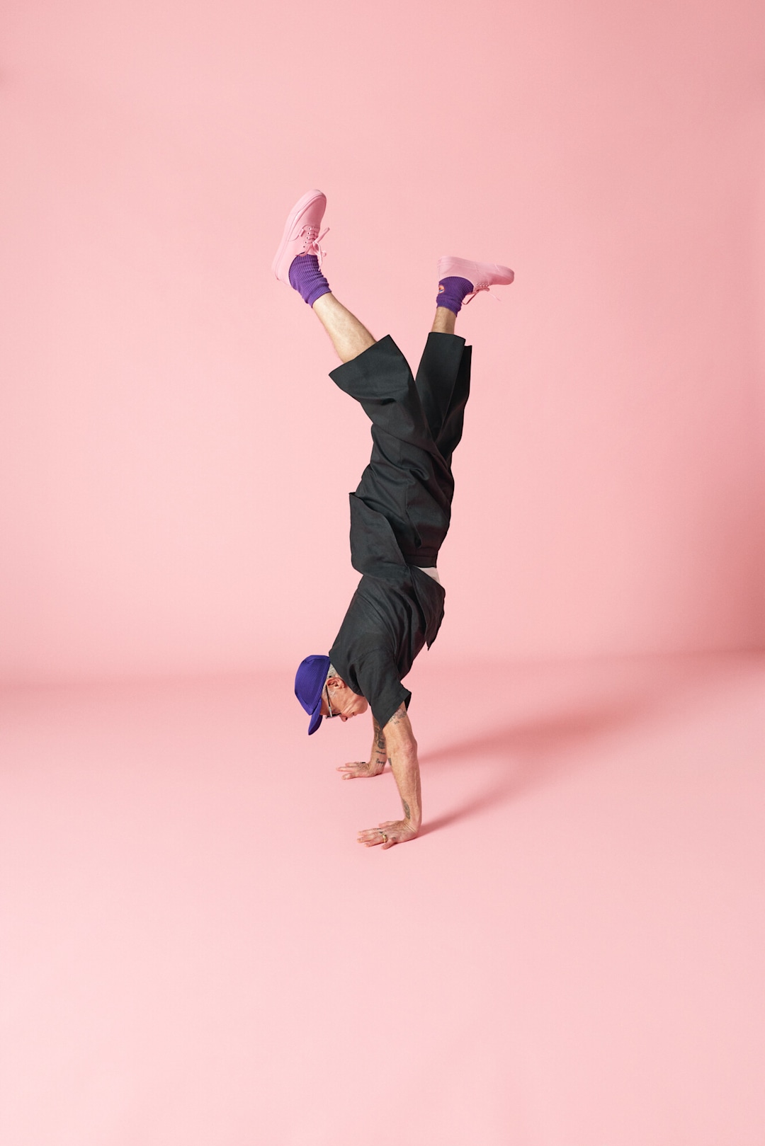 Flea doing a handstand with Vans x Atiba Cargo pant in black and Premium Authentic shoe in pink.