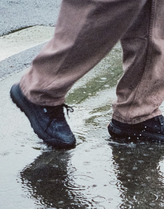 Someone walking in black MTE Crosspath shoes in a rainy street.