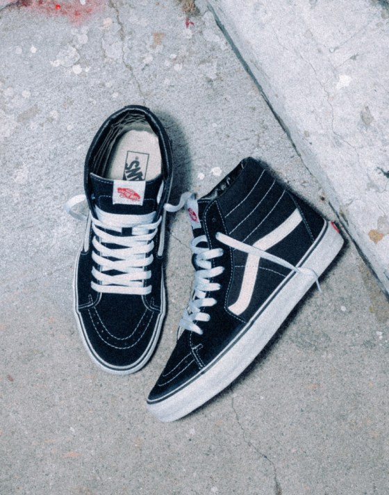 An overhead shot of black Sk8-Hi shoes with a white SideStripe with one shoe on its side.An overhead shot of black Sk8-Hi shoes with a white SideStripe with one shoe on its side.