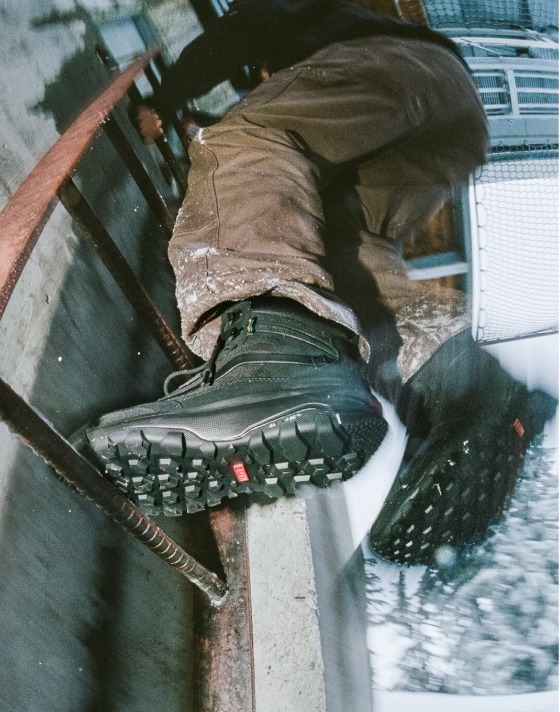 A close-up of someone wearing black MTE Crestline climbing the metal ladder of a building.