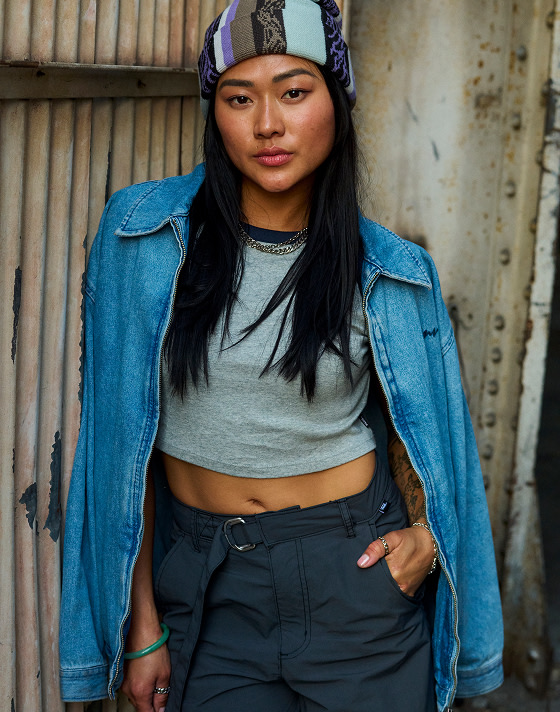 A woman wearing a gray t-shirt with navy pants and a denim overshirt.