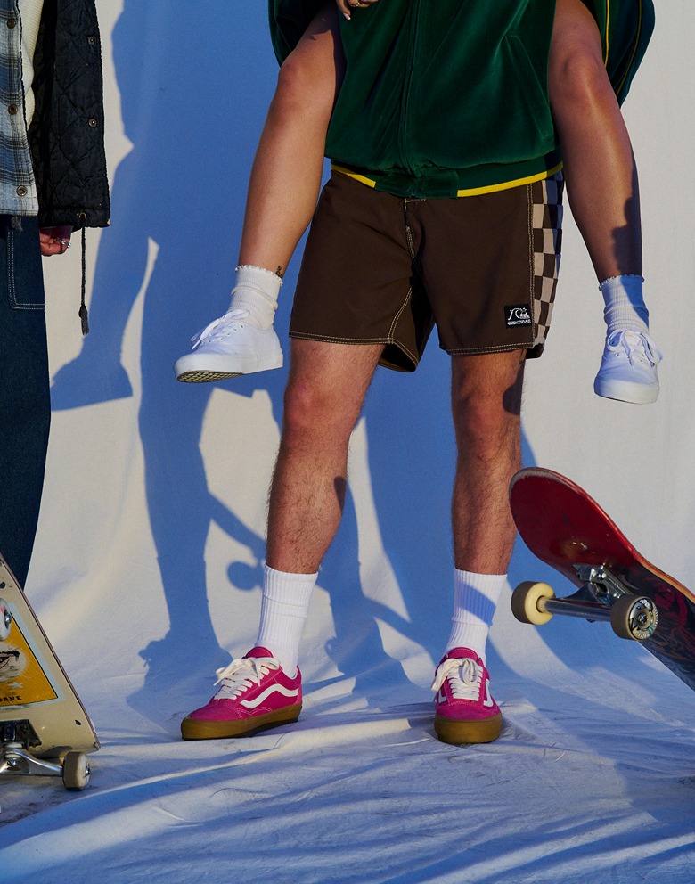 Men standing and wearing white Authentic shoes, red Old Skool, and black and white Checkerboard Classic Slip-On.