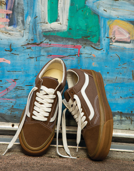 Sepia Brown Premium Old Skool shoes resting on a colorful wall of vibrant blue and pink paint.