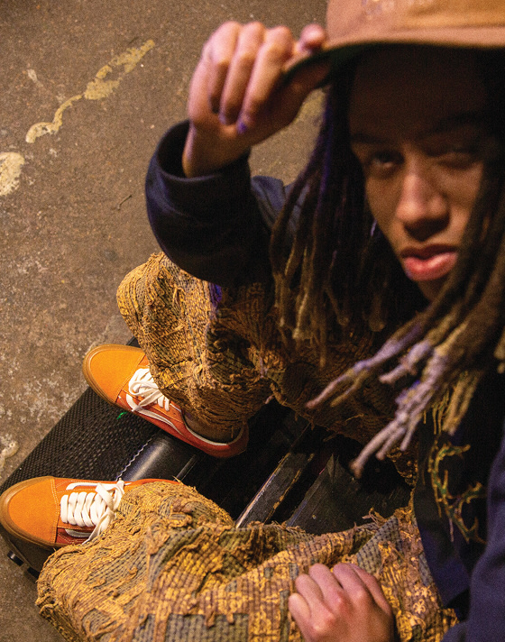A member from the Hip-Hop/Rap band Hi-Tech wearing Marmalade Orange Premium Old Skool shoes with a hand on his cap.