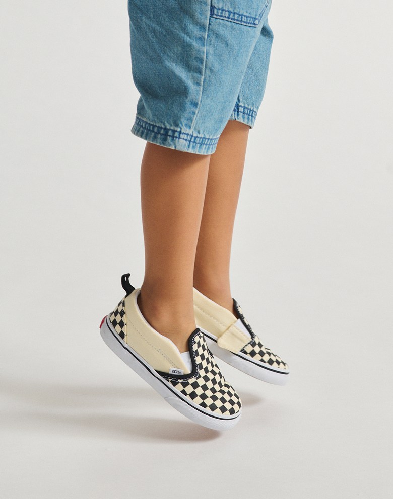 Close up shot of someone wearing the Kids Classic Slip-On shoes in Checkerboard pattern.