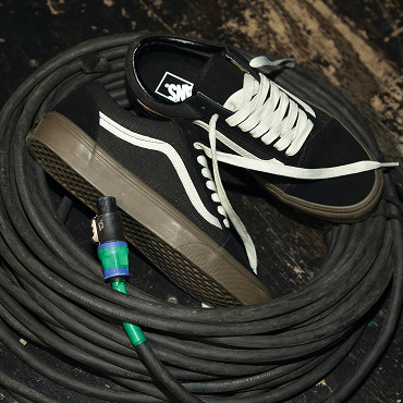 A pair of Black/Gum Old Skool shoes placed on top of black coiled cables. 