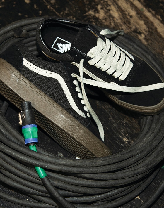 A pair of black Old Skool shoes laying in the middle of wire.
