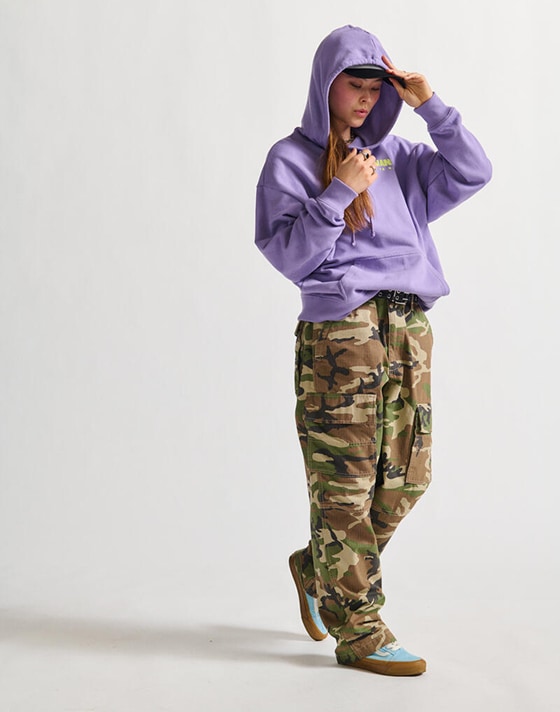 A woman with a purple hoodie wearing camo pants.