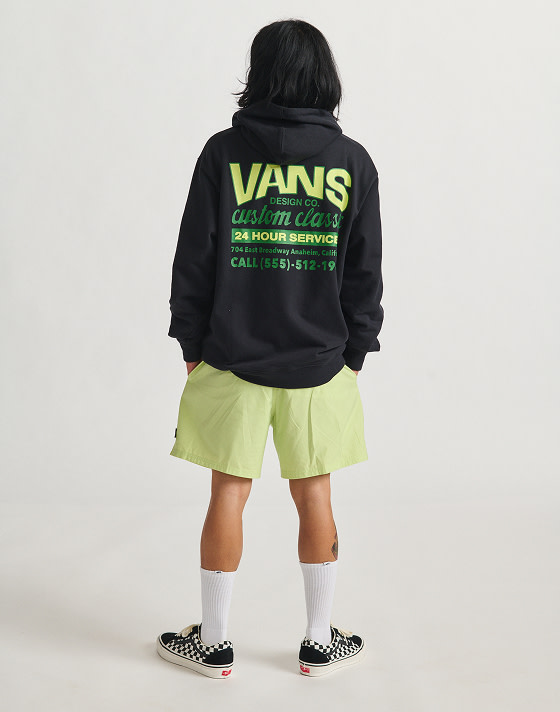 A man standing with his back to the camera wearing a vans hoodie sweatshirt and lime green shorts.