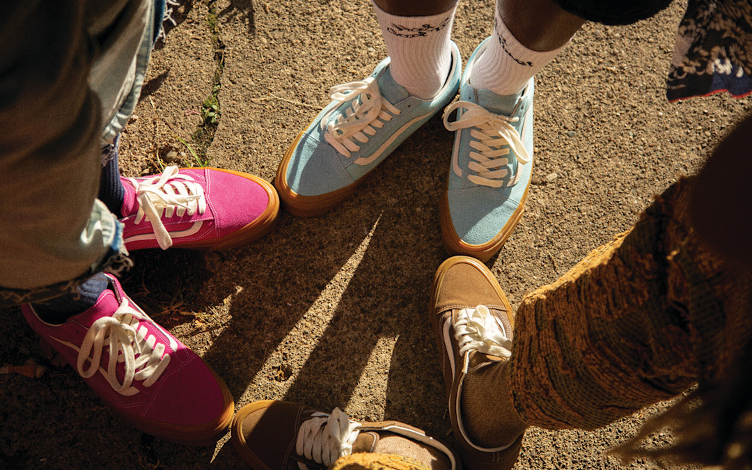 Three people wearing different colored premium old skool shoes standing in a circle