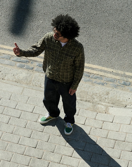 Two girls leaning against a wall wearing black vans old skool shoes and red authentic shoes with checkerboard socks.