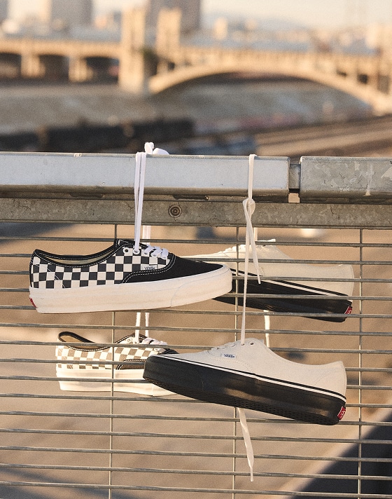 Two pairs of shoes hanging off a ledge in the city.