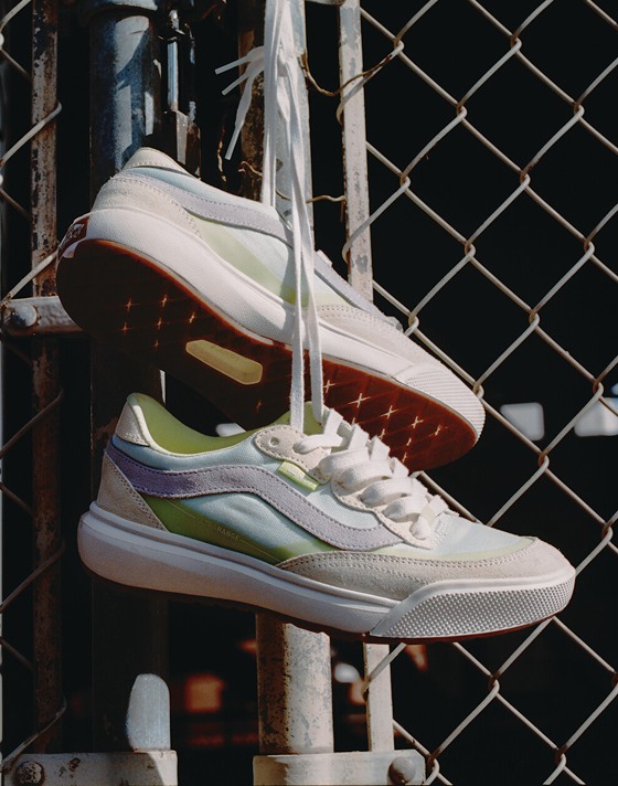 A pair of UltraRange 2.0 shoes hang from a cyclone fence with their laces tied together.