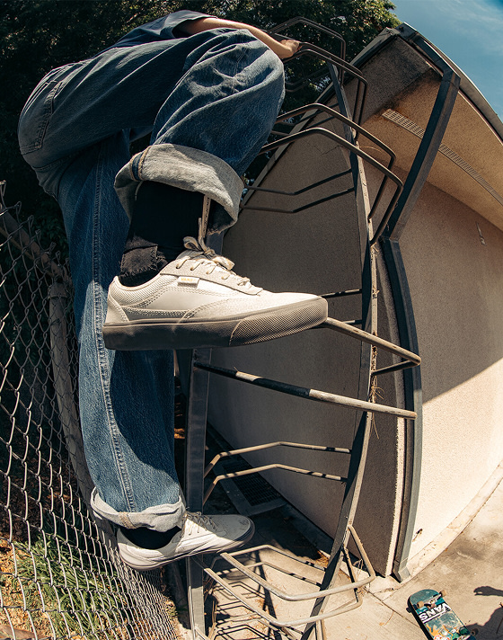 Skater Shiloh Catori climbing a ladder in blue jeans and gray Curren shoes.