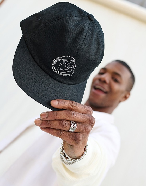 A person holding a green vans baseball cap 