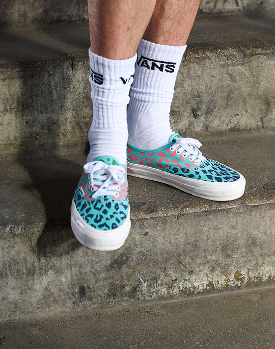 Somebody on concrete stairs wearing the Premium Authentic in Cheetah Pool Blue paired with white quarter socks with the Vans logo.
