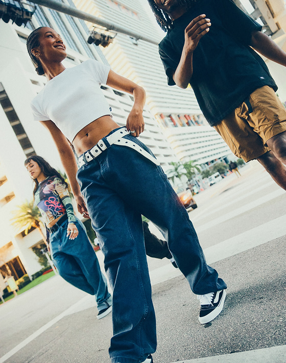 A group of friends walk in an intersection of a busy city street wearing Vans shoes and clothes.