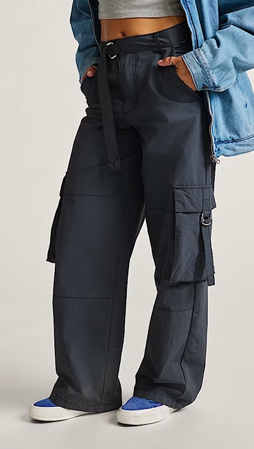 A chest-down shot of a woman in a gray crop top, Asphalt Grey Cobra Cargo pants, and a Stonewash Blue Pitstop Denim Jacket.