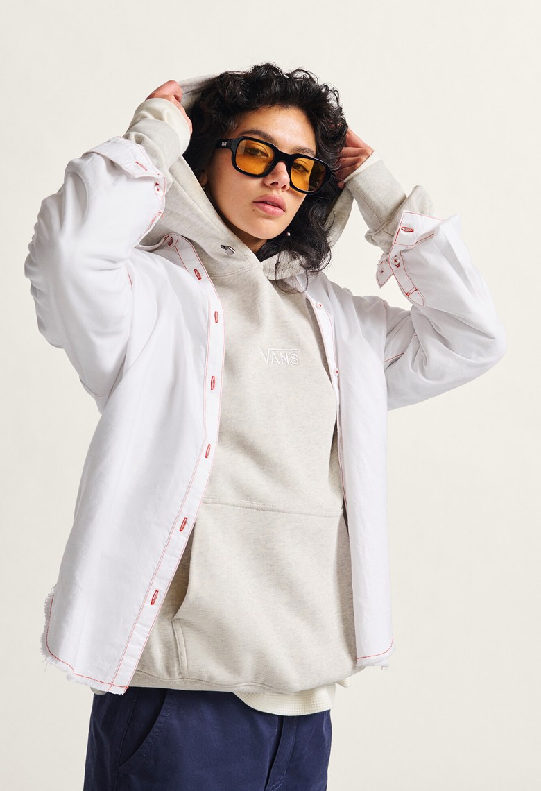 A woman pulling the hood of a Premium Logo Hoodie over her head wearing a white Gillian Button Up Shirt and sunglasses looking into the camera.