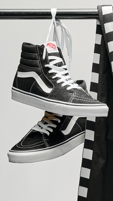 A pair of black and white Sk9-Hi hanging from their laces in a photography studio.