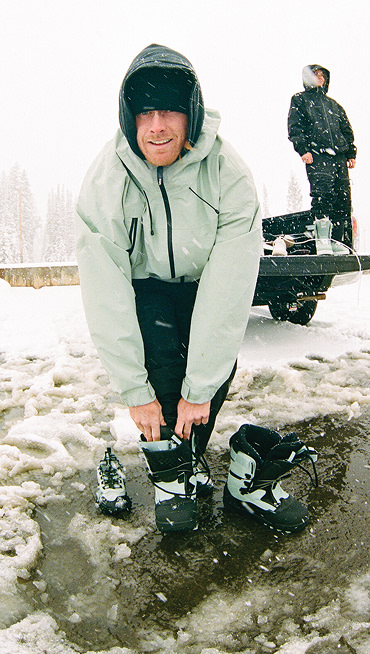 Vans Snow Team Rider Parker Szumowski puts on the Infuse snowboard boots in a parking lot wearing High Country 3L Outerwear in a snowy parking lot.