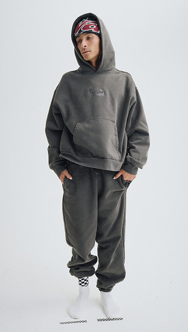 Wide shot of a man wearing a Premium Pullover Hoodie in Faded Black with a Vans Skull Beanie in Faded Black.