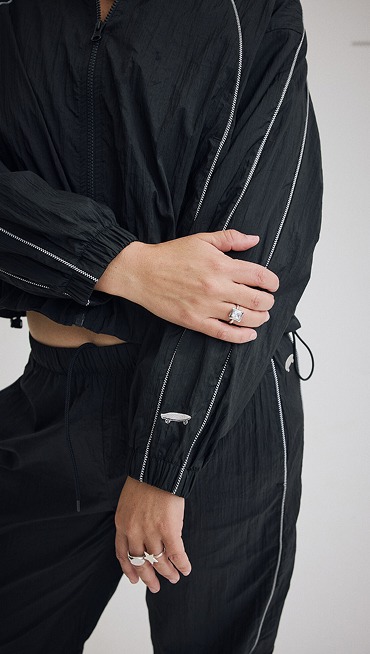 Close-up on the stitching and skateboard logo details on the black Nyla tracksuit.