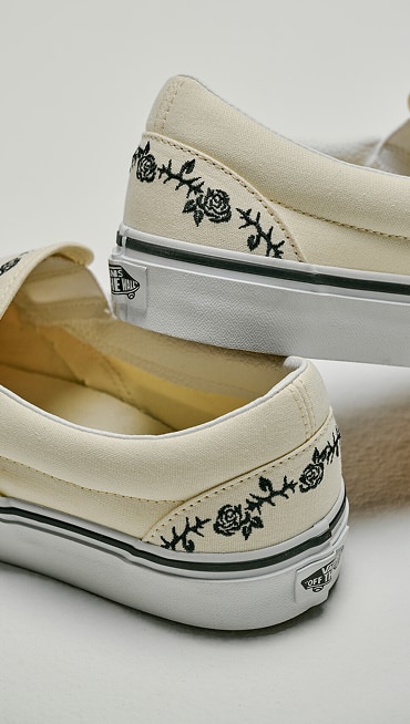 Close-up on the floral and barbed wire stitching on a white Classic Slip-On from the Embroidered Collection.