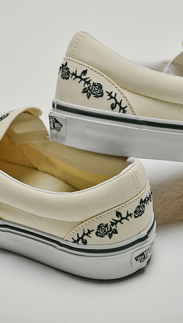 Close up on the heels of the Classic White Classic Slip-On Shoe with black embroidered roses and thorns.