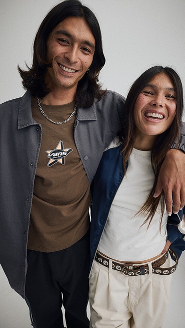 Waist up medium shot of a man with his arm around a woman. He’s wearing a Torrey Pigment Canvas Coaches Jacket, she’s wearing a Souvenir Jacket.