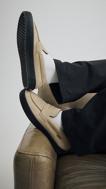 Close up of a man wearing a pair of the Incense Brown / Black Skate Loafer Shoes and kicking his feet up on the end of a couch.