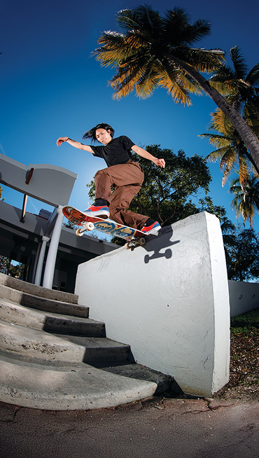 Wide shot of Daiki Hoshino outside skateboarding and grinding off a cement wall next to a flight of stairs wearing the Blue / Red Skate Era Shoe.